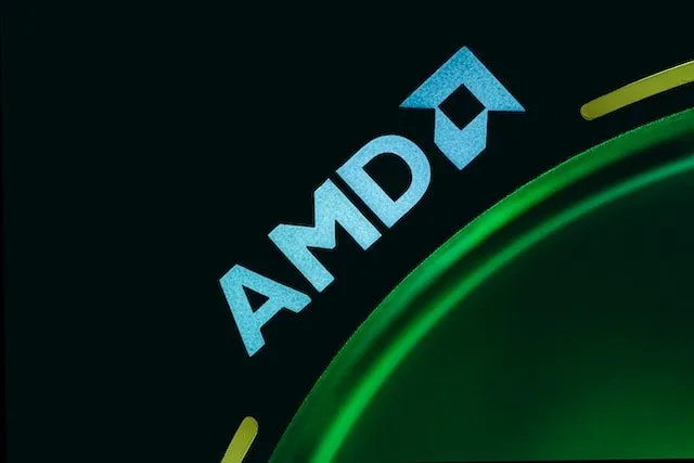 Стилізований логотип компанії AMD бірюзового кольору поруч із частиною великого зеленого світтячого кола на чорному тлі.