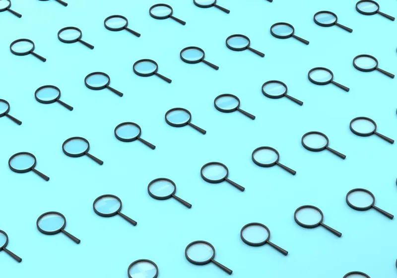 Repeated magnifying glasses on a blue background representing text verification and AI watermarking