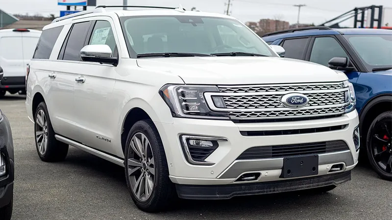 Великий білий позашляховик Ford Expedition з хромованою решіткою радіатора стоїть на парковці поруч із іншими автомобілями.
