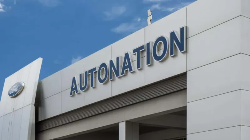 Сучасний фасад автодилера Autonation із великим написом та логотипом Ford на тлі блакитного неба.