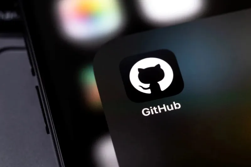 Чіткий логотип GitHub Octocat відображається на темному інтерфейсі комп'ютера з розмитим фоном робочого столу.