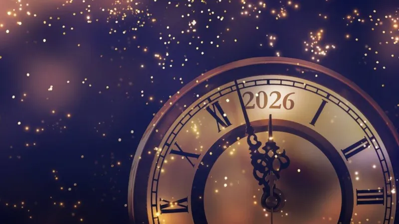 Золотистий годинник із римськими цифрами та написом 2026 оточений яскравими іскрами на темно-синьому фоні.