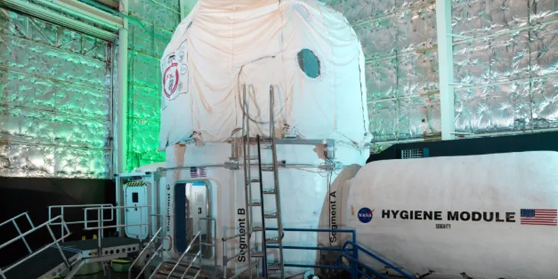 Космічний модуль під назвою Hygiene Module із логотипом NASA та американським прапором у лабораторії з фольгованими стінами.
