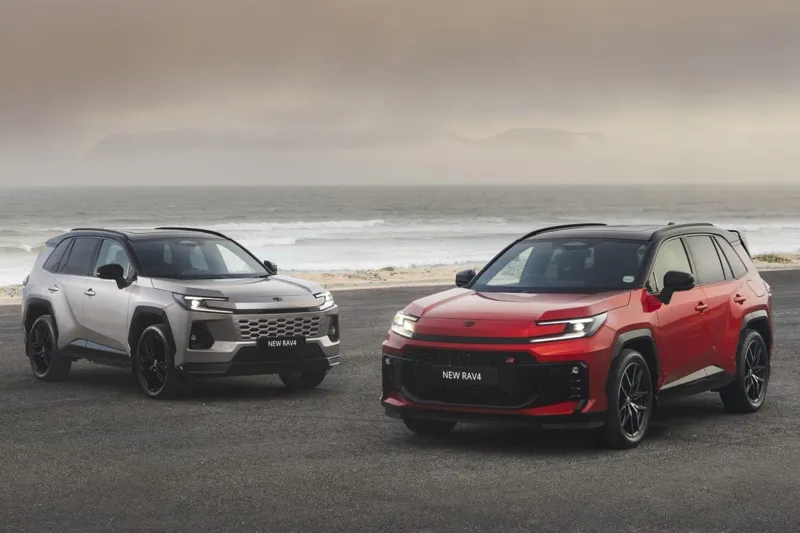 Два кросовери Toyota RAV4 різних кольорів стоять на мальовничому узбережжі, з видом на океан та туманне небо.