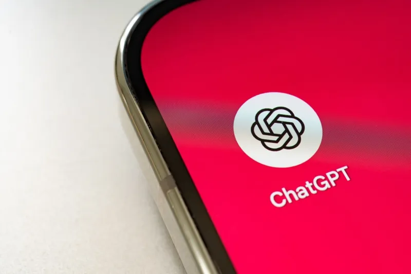 Крупний план екрана сучасного смартфона з білою іконкою ChatGPT на яскравому рожевому фоні.
