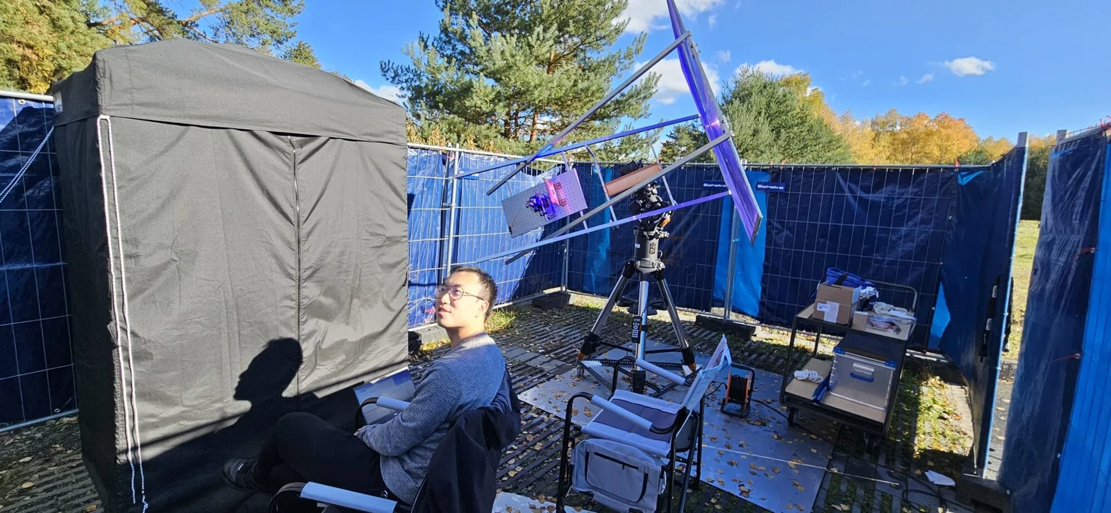 Researcher Cheng Li standing beside an outdoor sunlight-driven quantum entanglement experimental setup