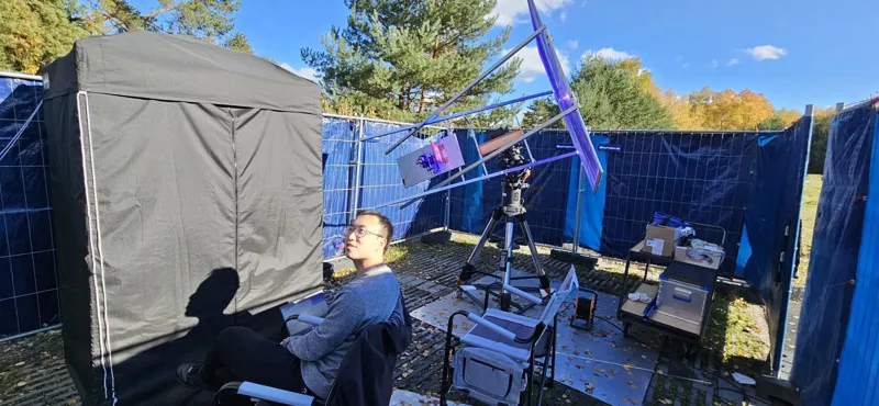 Researcher Cheng Li standing beside an outdoor sunlight-driven quantum entanglement experimental setup