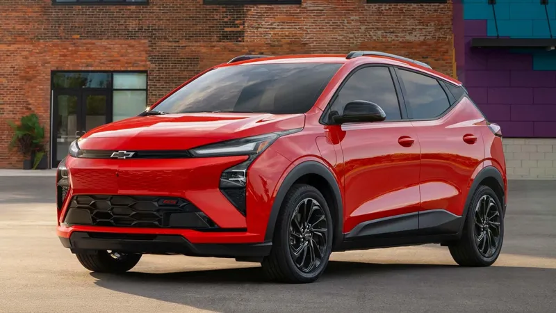 Червоний кросовер Chevrolet Blazer EV припаркований перед сучасною цегляною будівлею з фіолетовими елементами фасаду.