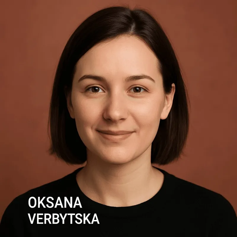 Портрет Оксани Вербської у чорній футболці на нейтральному коричневому фоні, яка дивиться прямо в камеру з легкою посмішкою.
