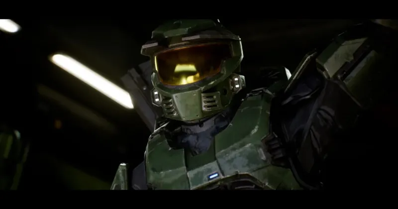 Герой гри Halo у характерній зеленій командній броні та шоломі з золотистим склом у темному приміщенні.