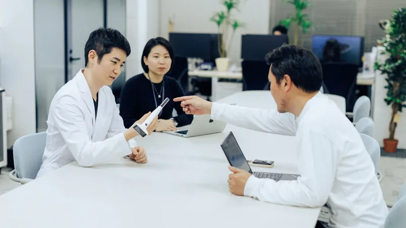 A medical professional examining a patient's throat using the Nodoca AI optical device.