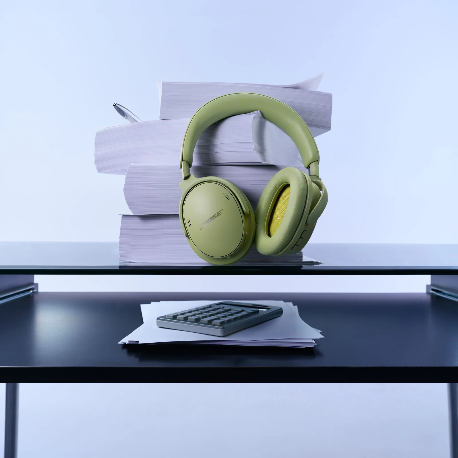 Bose QuietComfort Headphones 2nd Gen in Eucalyptus Green sitting on a glass table next to stacked books.
