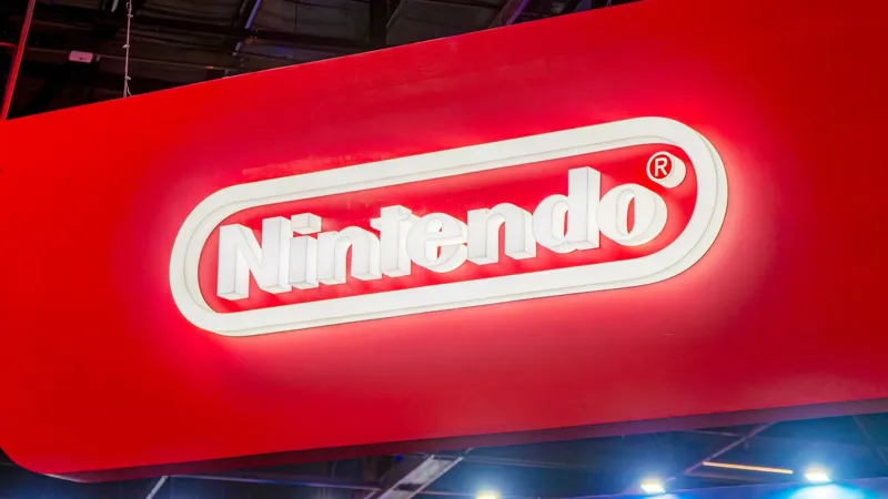 Великий підсвічений логотип Nintendo білого кольору на яскраво-червоному фоні у виставковому залі.